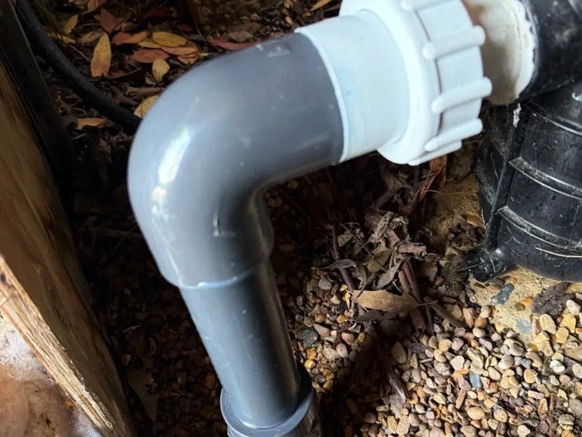 New grey PVC-U elbow and white union fitted to the pump on a gravel floor after the repair